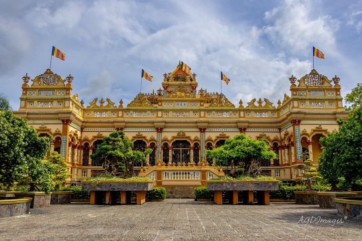 Ornate Buddhist temple with flags and trees.