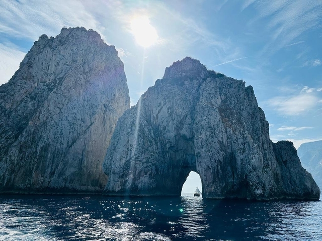 Dramatic rocky cliffs with an archway and blue sky.