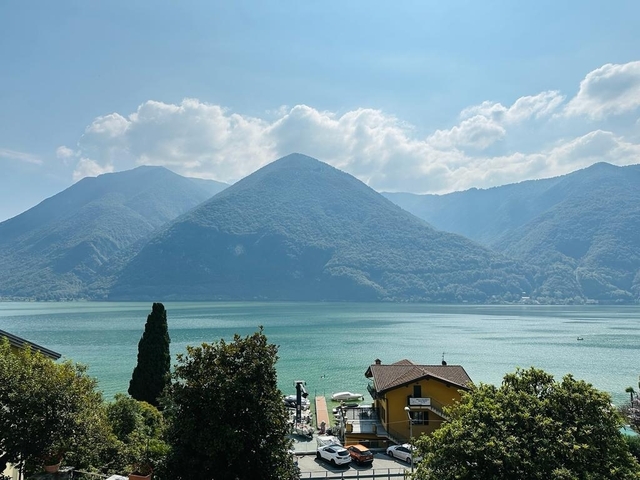 Scenic lake view with mountains and a small house near the shore.