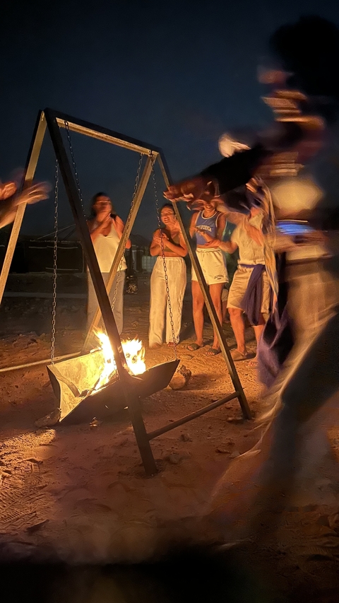 Group of people warming by an outdoor fire at night.