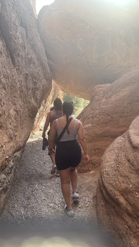 Two people walking through a rocky passage.