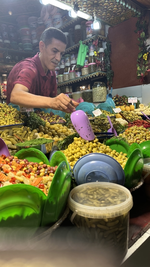 Hand arranging colorful olives in a market.