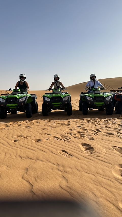 People riding quad bikes on a desert dune.