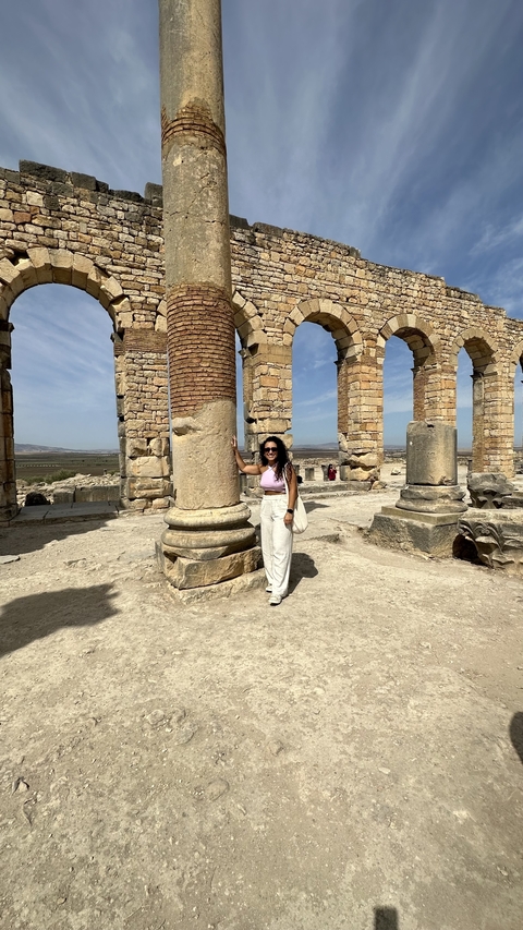 Tourist posing near historical pillars.