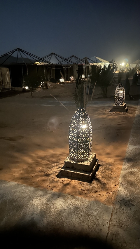 Decorative lit lanterns on a sandy path at night.