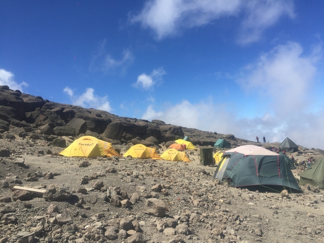 Rocky campsite with rows of colorful tents.