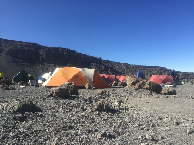 Trail of tents set up in a rocky mountainous area.