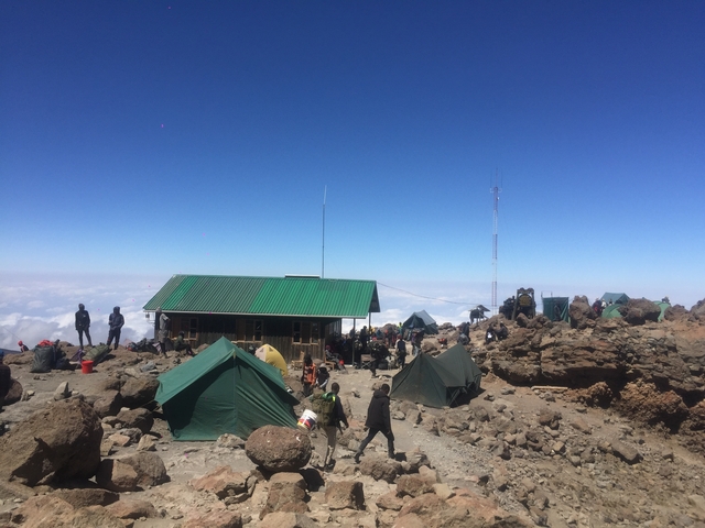 High-altitude camp with several tents and people.