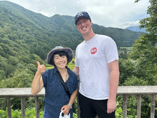 Two people smiling with a mountainous backdrop.