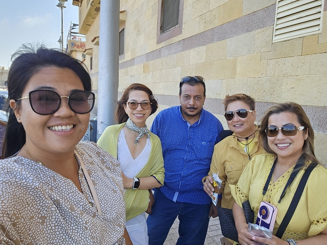 A group of five people smiling in front of a stone wall.