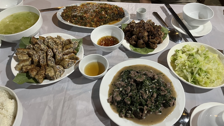 Table with various Vietnamese dishes including fried rolls and vegetables.