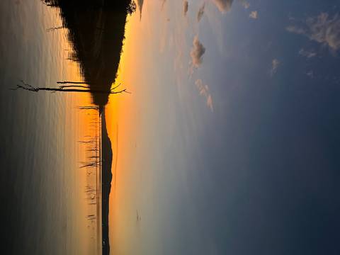 Sunset view over a lake with silhouettes of trees.