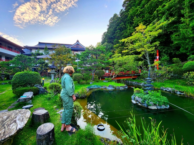 A person exploring a beautiful garden with traditional buildings.