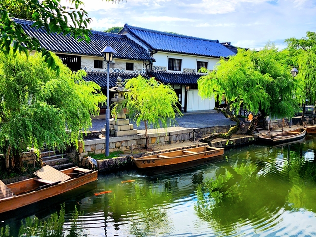 Scenic canal with traditional boats and green trees.