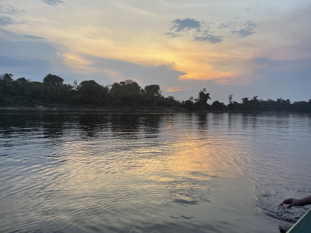 Sunset reflected on a river with a cloudy sky.