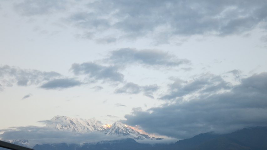 Snow-capped mountains peeking through a cloudy sky.