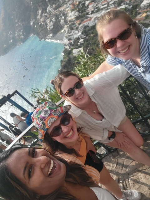 Two smiling women overlooking a beautiful coastal view.