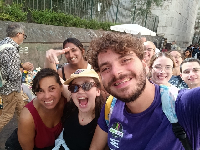 A group of smiling people posing for a selfie outdoors.