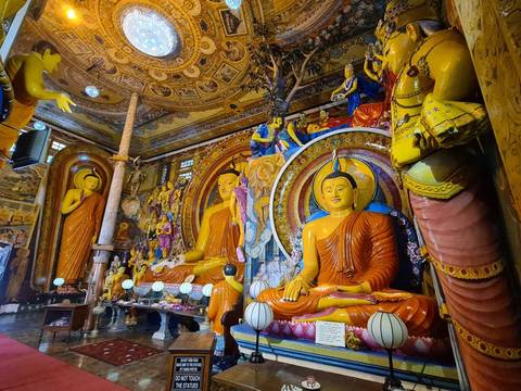Buddhist statues in a colorful temple interior with ornate decorations.
