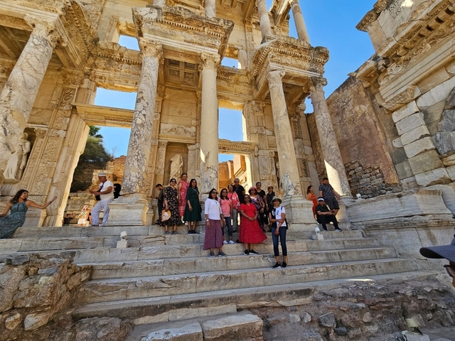 Group of tourists posing on the steps of an ancient building.
