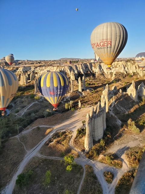 Hot air balloons flying over a rocky landscape at sunrise.