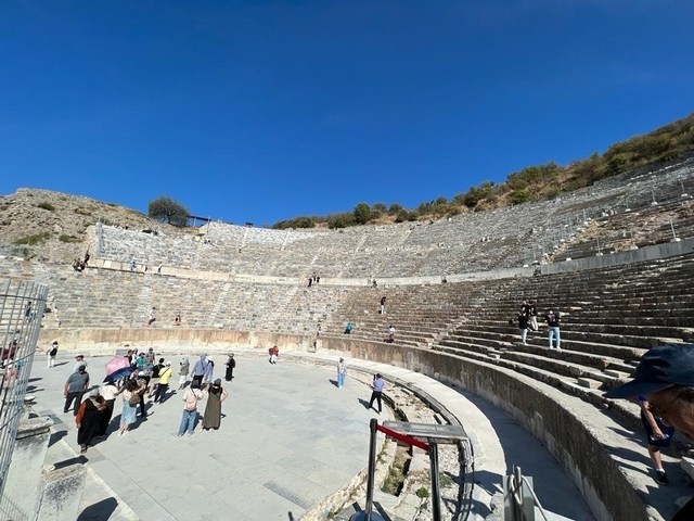 Ancient amphitheater with tourists exploring.