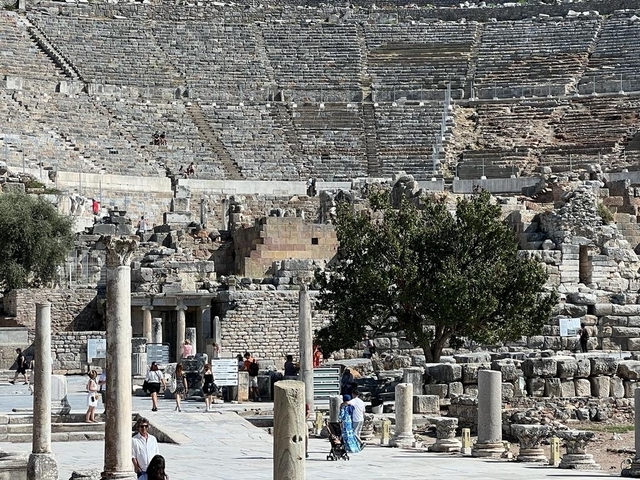 Ruins of an ancient theater with visitors.