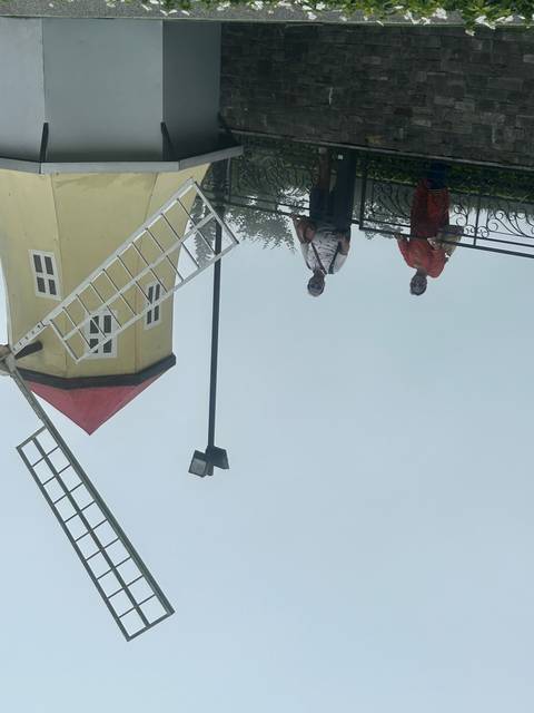 People standing by a model windmill structure.