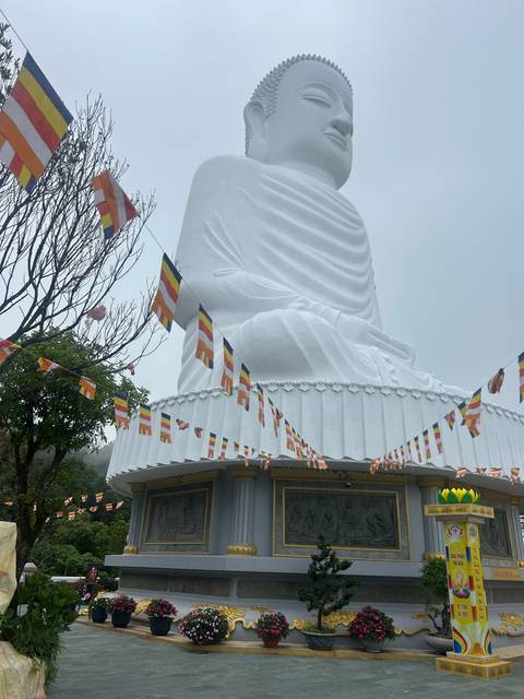Statue of a large reclining Buddha under cloudy skies.