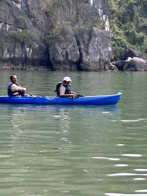 Kayaker paddling through calm waters with cliffs.