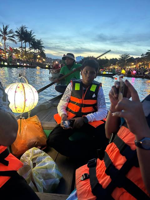Family in a boat holding brightly lit lanterns.