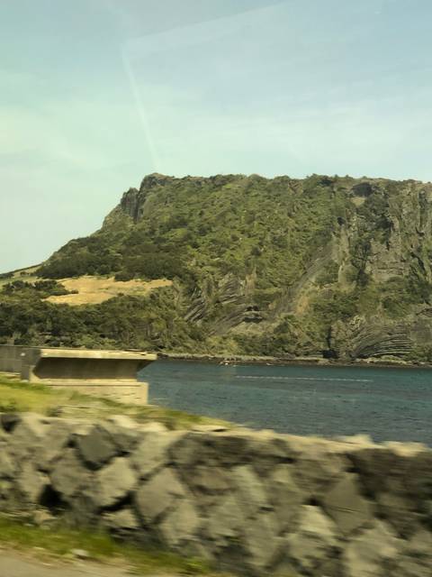 Blurry image of a large rock formation near a water body.