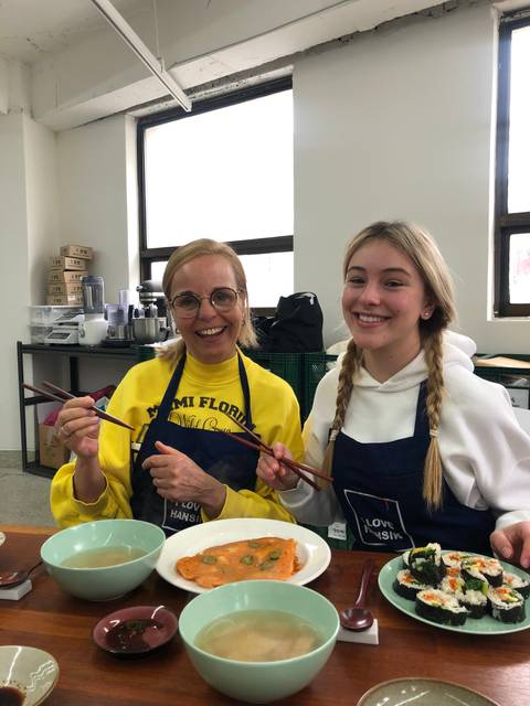 Two women sitting at a table with various dishes in front of them.