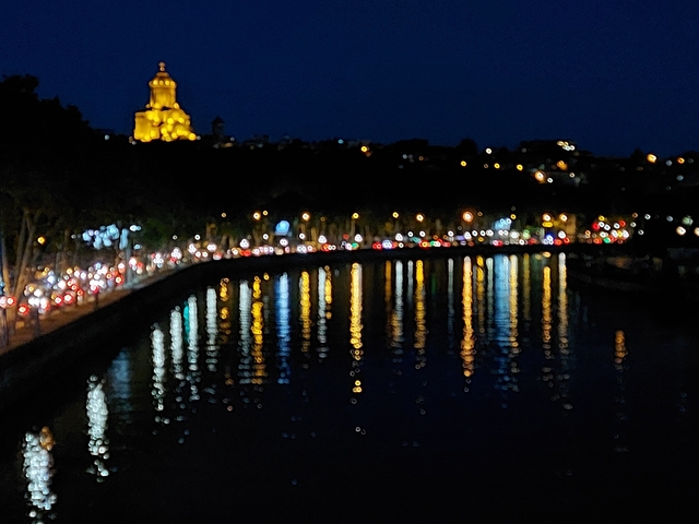 Blurry night view of a river with lights reflecting.