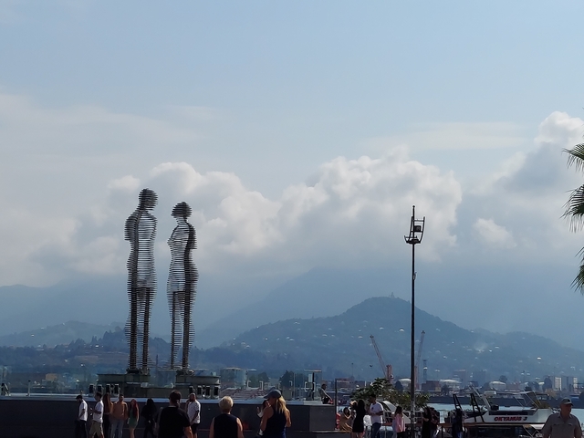 Silhouette of two metal sculptures against mountains.