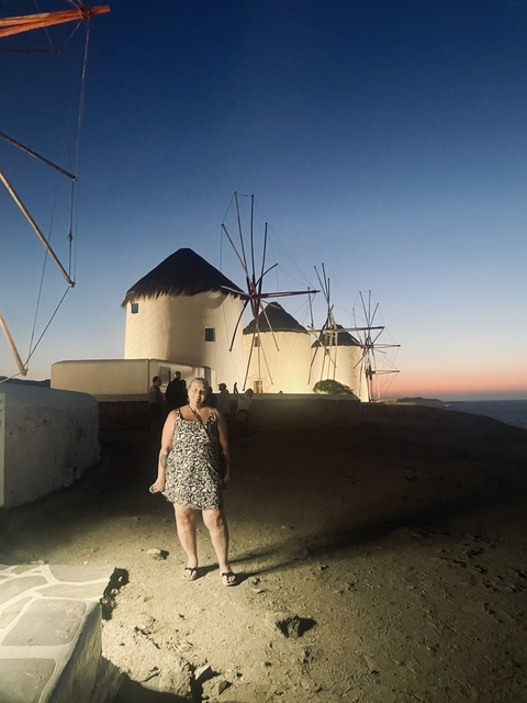 Person standing in front of windmills at dusk.