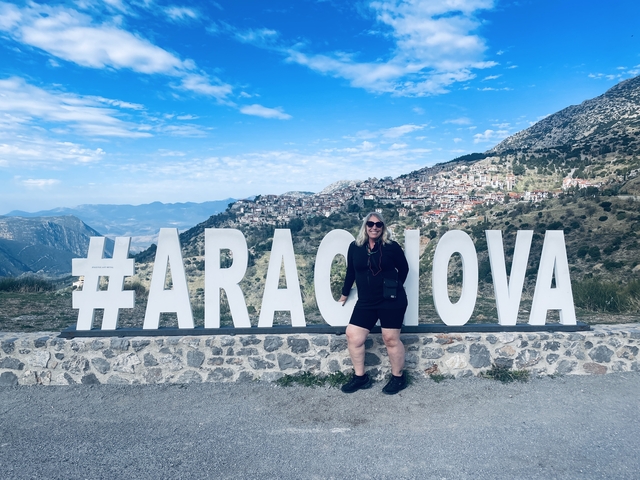 Individual posing in front of a large hashtag sign and mountain town.