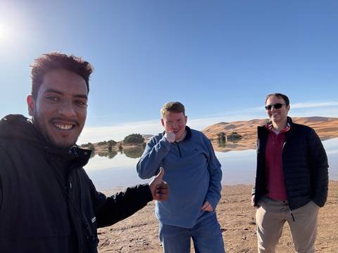 Three people upside down, posing in the desert landscape.