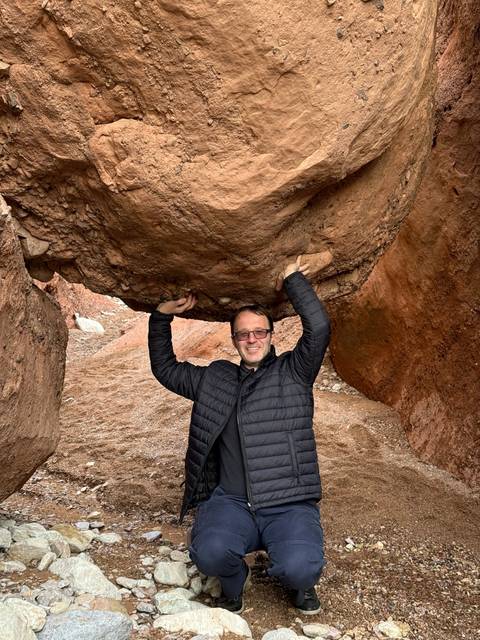 A person holding a rock in a dry, rocky area.
