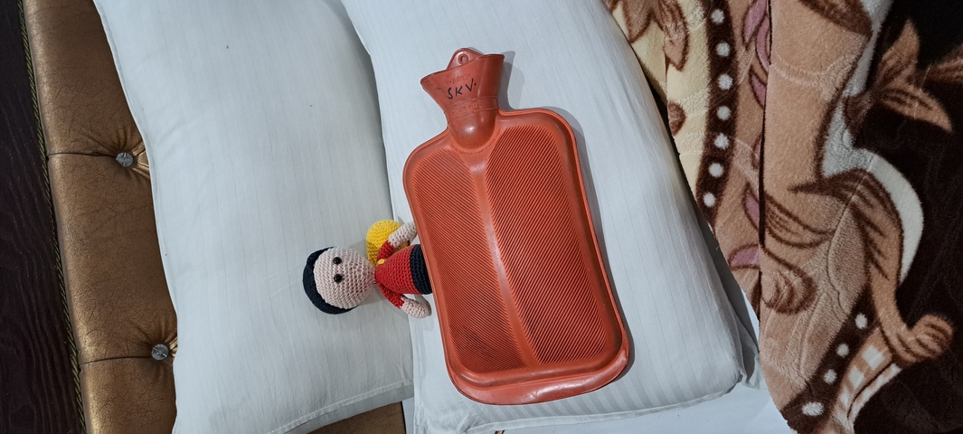Hot water bottle and toy on a bed.