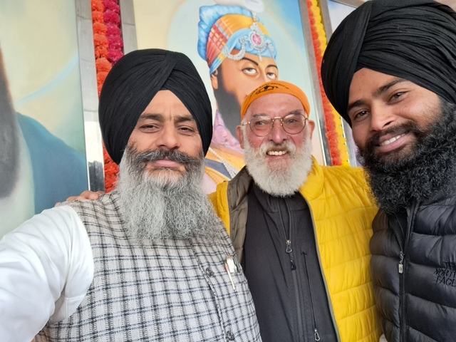 Three men smiling for a group photo indoors.