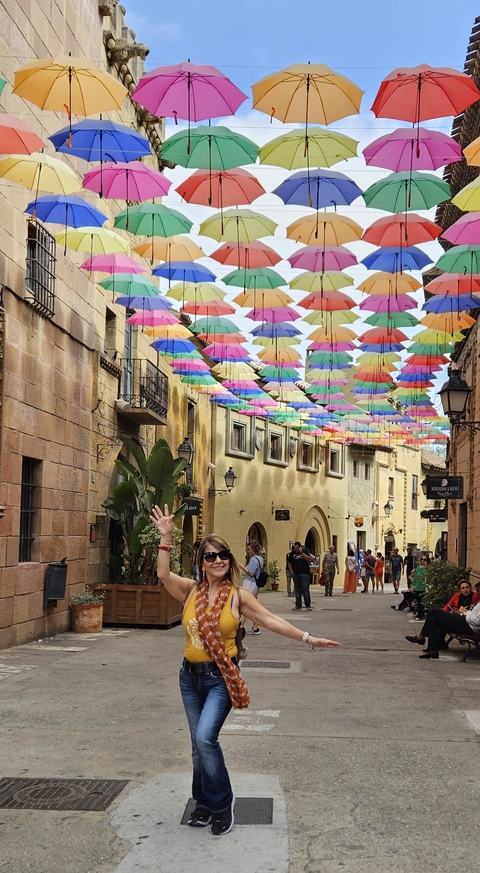 Street with colorful umbrellas hanging above, and people walking.