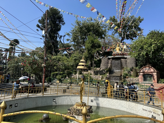 Decorated park with statues and greenery, people walking around.
