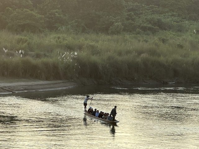 People on a traditional boat in a river surrounded by vegetation.