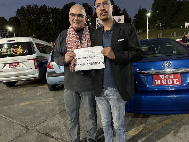 Two people standing with a welcome sign at an airport.
