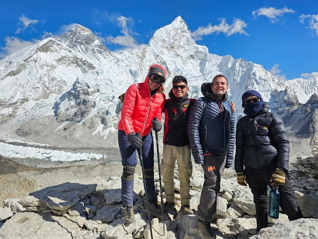 Four people posing in front of snowy mountains.