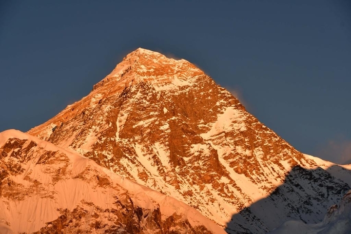 Peak of a mountain glowing in the light of sunrise.