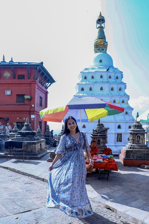 Person with colorful umbrella in front of religious and cultural structures.