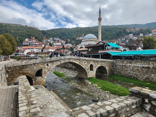 Stone bridge over a creek in a historic town area.
