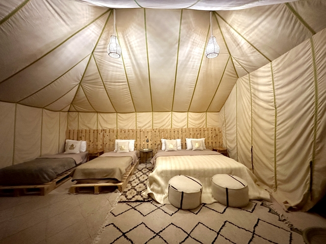 Interior of a desert tent with bedding and lamps.